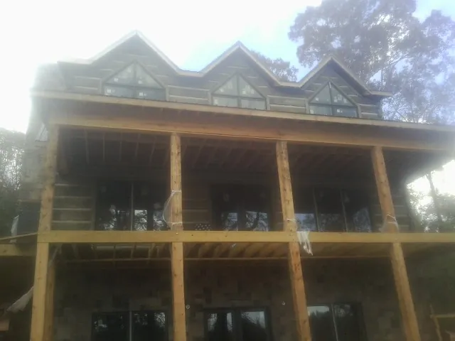 Dormers and porch framing on a large log home under construction — Roof Coating work by our crew in New Hampton