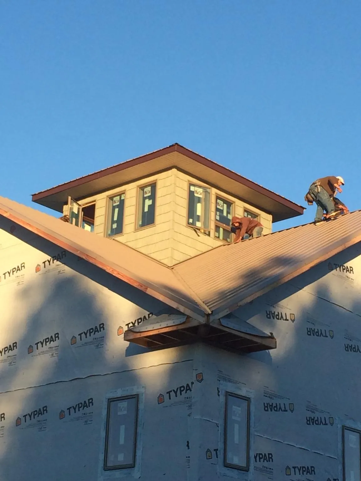Roofers working around a rooftop cupola on a new metal roof at sunset — Roof Waterproofing in New Hampton by Roofing Brothers